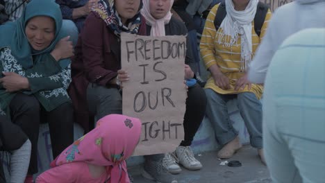 Afghan-woman-holding-sign-''Freedom-is-our-right''-Sappho-Square-Mytilene-following-death-of-Afghan-man-in-Moria-Refugee-Camp,-MEDIUM-SHOT