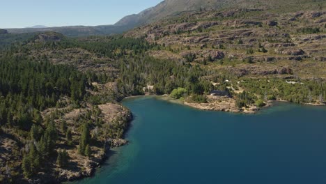 Aerial-pan-right-of-Epuyen-lake-surrounded-by-pine-tree-forest-and-mountains,-Patagonia-Argentina