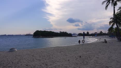 People-enjoying-the-sunset-at-Siloso-beach,-Sentosa-Island