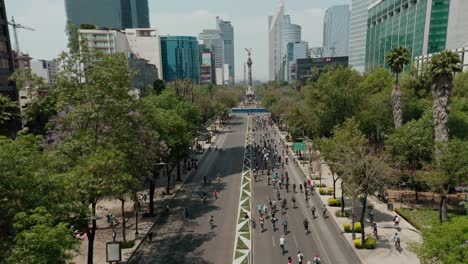 Drone-Aéreo-De-Gran-Angular-Sobre-Ciclistas-En-La-Carretera-Cerca-Del-Monumento-A-La-Independencia