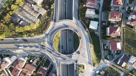 Drone-traffic-footage-as-cars-drive-at-a-fixed-intersection-from-above-at-sunset