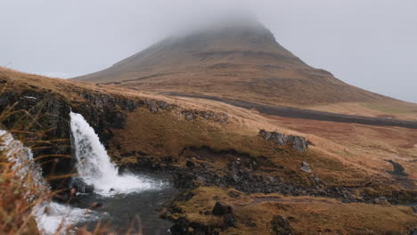 Base-of-Kirkjufellsfoss-Waterfall,-mist-covered-Kirkjufell-in-background
