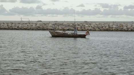 Un-Barco-De-Pesca-De-Calamares-Amarrado-En-El-Puerto-Deportivo-De-Khao-Takiab,-El-Barco-Protegido-Por-Un-Muelle-Rocoso-En-Una-Hermosa-Tarde-De-Puesta-De-Sol,-Hua-Hin,-Tailandia