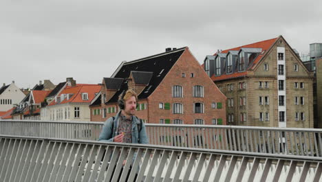 People-Walking-At-Pedestrian-Bridge-In-Nyhavn,-Copenhagen,-Denmark-With-Waterfront-Hotel-Buildings-In-Background