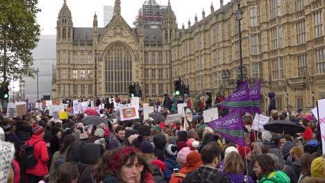 Large-crowd-of-activists-protesting-for-women's-rights-in-front-of-the-Houses-of-Parliament-in-London,-UK