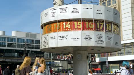 A-group-of-young-tourists-explores-the-World-Time-Clock-monument-in-Alexanderplatz,-Berlin