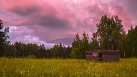 heavy-cloudscape-timelapse-over-a-green-boreal-forest-and-meadow-with-a-Thermowood-country-hut