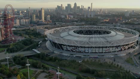 Vista-Aérea-Del-Estadio-De-Londres,-Hogar-Del-Club-De-Fútbol-West-Ham-United-En-El-Reino-Unido-Con-Vista-Del-Horizonte-De-La-Ciudad-De-Londres-En-Segundo-Plano