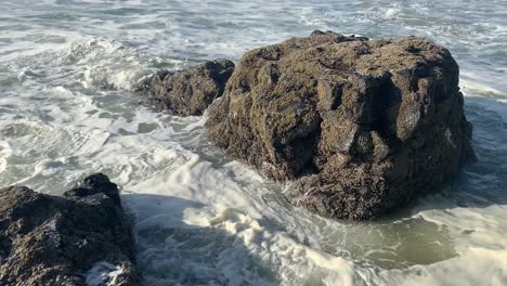 Foamy-Ocean-Waves-Crashing-Against-Rock-At-The-Beach