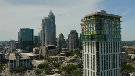 Slow-Aerial-Flight-Past-Modern-Apartment-Building-with-Charlotte-Skyline-in-Background