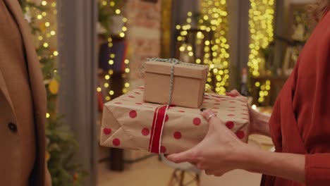 Husband-giving-two-boxes-of-presents-to-his-wife-on-Christmas-eve-night-at-the-interior-of-their-home-just-before-dinner