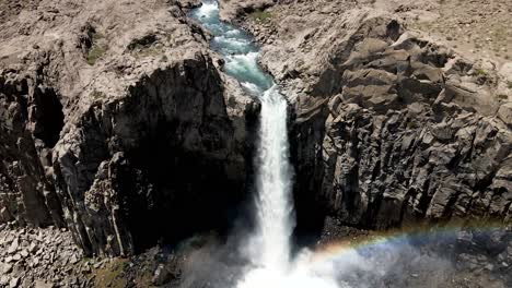 Aerial-view-of-a-crane-shot-of-a-powerful-waterfall-that-generates-a-rainbow-as-it-falls-by-the-action-of-its-power