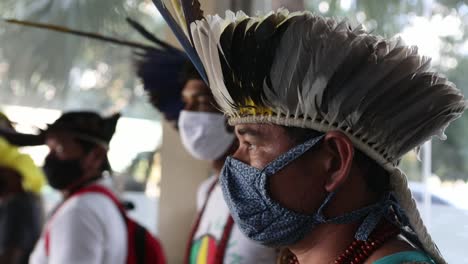 Indigener-Mann-Eines-Stammes-Im-Amazonas-Regenwald-Bei-Einem-Protest,-Der-Einen-Traditionellen-Federkopfschmuck-Und-Eine-Schützende-Gesichtsmaske-Trägt