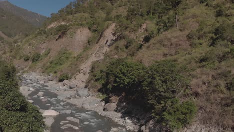 river-flowing-with-mountain-water-in-remote-tropical-region-surrounded-by-trees-in-benguet-philippines-slow-approaching-aerial