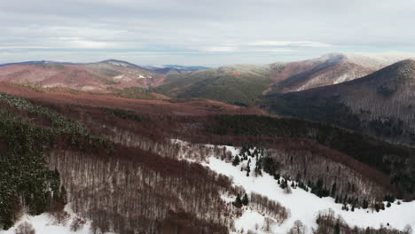 Wide-angle-flyover-above-forested-foothills-with-a-light-dusting-of-snow