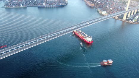 Large-Container-Ship-leaving-Hong-Kong-bay-under-Stonecutters-bridge,-Aerial-view