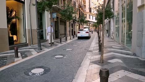 Enge-Innenstadtstraße-Von-Sevilla-Mit-Vorbeifahrendem-Weißem-Taxi,-Handheld-Ansicht