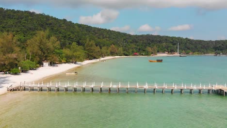 Koh-Rong-beach-in-Cambodia,-popular-tourist-destination-with-pier,-fly-back-aerial-drone-view