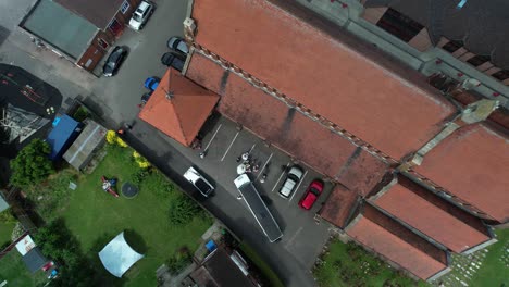 Rising-aerial-view-above-newlywed-couple,-Limousine-and-wedding-ceremony-guests-at-charming-village-church