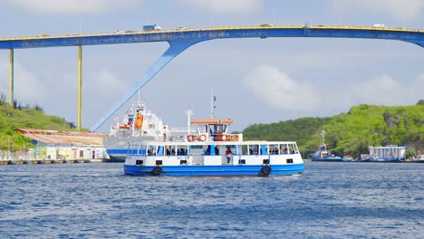 Ferry-Turístico-Que-Cruza-La-Famosa-Bahía-De-Sint-Anna-Debajo-Del-Puente-De-La-Reina-Juliana-En-Willemstad,-Curacao