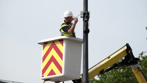 A-worker-in-a-cherrypicker-on-a-crane-installs-a-rotational-close-circuit-television-camera-on-a-lamppost