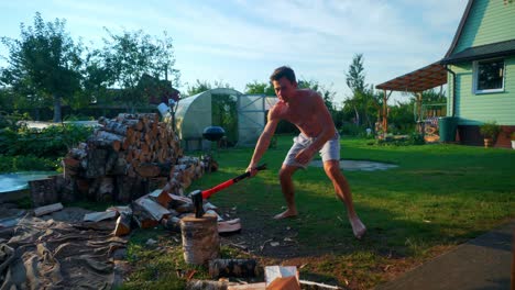 Strong-Young-Man-Holding-An-Axe-Splitting-A-Piece-Of-Firewood-Outdoors-In-Lithuania
