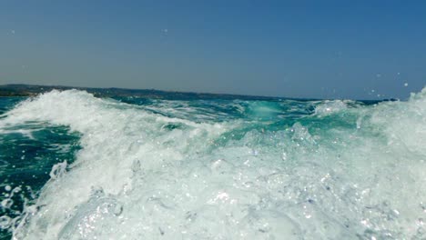 Low-angle-water-surface-pov-of-motorboat-wake-trail-over-blue-seawater