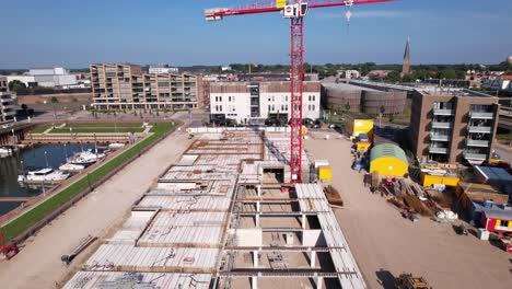 Downward-tilt-showing-large-red-crane-revealing-the-foundation-and-beginning-layer-of-luxury-apartment-Kade-Zuid-complex-being-build-in-former-industrial-area