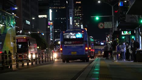 Seoul,-Südkorea-15.-September-2021-–-Menschen-In-Masken-Warten-Auf-Einen-Bus,-Wenn-Viele-öffentliche-Stadtbusse-Nachts-Auf-Busspuren-Im-Zentrum-Von-Seoul,-Dem-Busbahnhof-Gangnam-Station,-Vorbeifahren