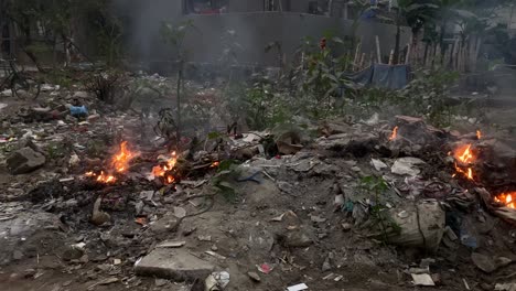 Schuss-Von-Feuer,-Das-Tagsüber-Aus-Dem-Müll-Nahegelegener-Häuser-In-Dhaka,-Bangladesch,-Brennt
