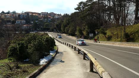 Los-Vehículos-Previos-A-La-Carrera-Pasan-Por-La-Carretera-Delante-De-Los-Ciclistas