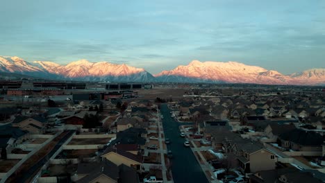 Suburban-neighborhood-with-Silicon-Slopes-at-Lehi,-Utah-at-sunset---pull-back-aerial-flyover