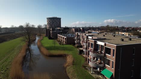 Aerial-approach-of-towering-building-of-service-flat-elderly-residential-home-in-Dutch-tower-town-with-lower-apartment-buildings-in-the-foreground