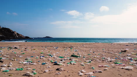 Verschmutzter-Müll-Aus-Plastik-Und-Papier-An-Einem-Strand-Mit-Türkisfarbenem-Wasser-Im-Hintergrund-An-Einem-Sommertag-In-Binh-Hung,-Vietnam