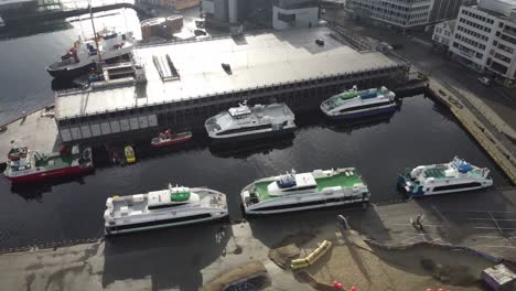 Several-high-speed-passenger-boats-is-moored-alongside-in-Stavanger-harbour-Norway---Aerial-Ascending-birdseye-aerial-with-rotation-revealing-full-harbour