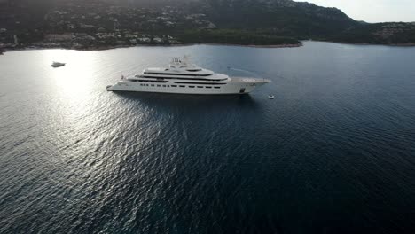 Aerial-approach-to-the-Dilbar,-a-third-biggest-private-luxury-yacht-of-the-Russian-billionaire-oligarch-Alisher-Usmanov-anchoring-on-the-emerald-waters-near-Porto-Cervo-in-Sardinia
