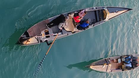 Vista-Aérea-De-Góndolas-En-Movimiento-Con-Turistas-A-Bordo-En-El-Canal-De-Venecia,-Italia