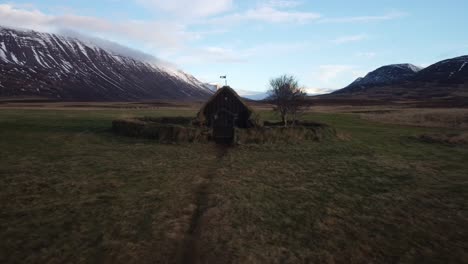 Vista-Aérea-Tire-Hacia-Atrás-De-Una-Joven-Caminando-Hacia-La-Iglesia-En-Islandia