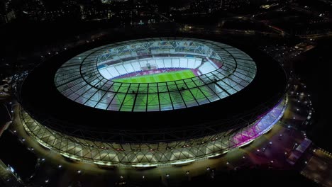 Aerial-view-futuristic-illuminated-official-West-Ham-united-club-football-arena-at-night
