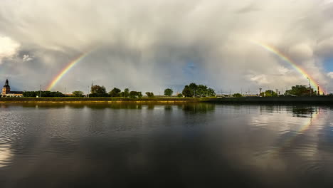 Time-lapse-shot-of-beautiful-Rainbow-over-Riga-City-and-Daugava-River-in-motion---Clouds-flying-at-blue-sky