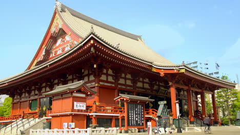 Asakusa,-Tokio,-Japón,-Alrededor-De-Abril-De-2020:-Gente-Caminando-En-Un-Auténtico-Templo-Japonés-Con-Una-Hermosa-Decoración-Artesanal-En-El-Techo-Y-La-Pared-En-El-Soleado-Día-De-Primavera
