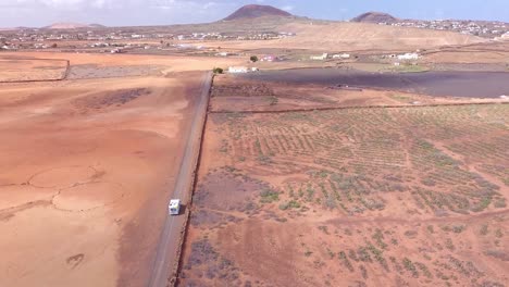 Big-motorhome-crossing-astonishing-red-desert-in-Fuerteventura,-Spain