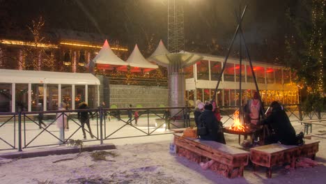 Menschen,-Die-Während-Der-Weihnachtsferien-In-Der-Nähe-Eines-Lagerfeuers-Im-Winter-In-Oslo,-Norwegen,-Auf-Der-Eisbahn-Schlittschuh-Laufen