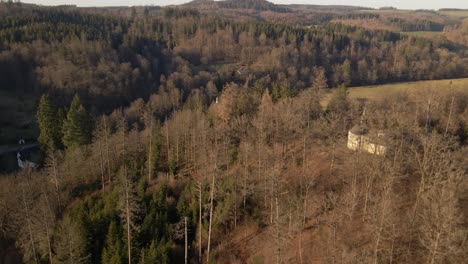 A-small-chapel-towering-on-a-steep-hill-over-a-German-water-castle-during-sunset