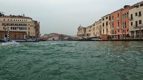 Water-surface-pov-of-Venice-seen-from-ferry-boat-on-Canal-Grande-with-Ponte-Degli-Scalzi-bridge-in-background,-Italy