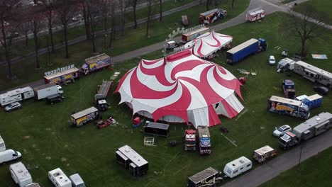 Planet-circus-daredevil-entertainment-colourful-swirl-tent-and-caravan-trailer-ring-aerial-view-descending-tilt-up