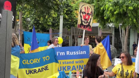 Woman-standing-with-a-placard-colored-in-the-national-flag-of-Ukraine,-stating-I-am-Russian,-I-stand-with-Ukraine