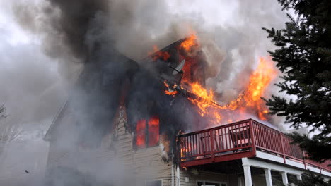 Water-from-a-Fire-Hose-Rains-Down-on-a-Burning-Three-Story-Residence-Completely-Engulfed-in-Flames-and-Smoke