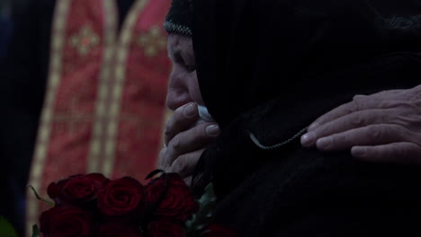 Una-Anciana-Vestida-De-Negro-Llora-Con-Un-Pañuelo-En-La-Boca-Mientras-Sostiene-Rosas-Rojas-Oscuras-En-El-Funeral-De-Un-Soldado-Ucraniano-Caído-Durante-La-Invasión-Rusa-Del-País