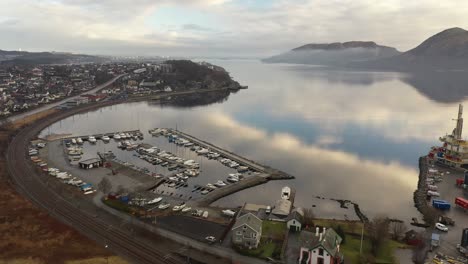 Sandnes-marina-and-Somaneset-in-Lura-bay---Norway-aerial-with-beautiful-sky-reflections-in-fjord---Railway-sorlandsbanen-passing-close-to-marina